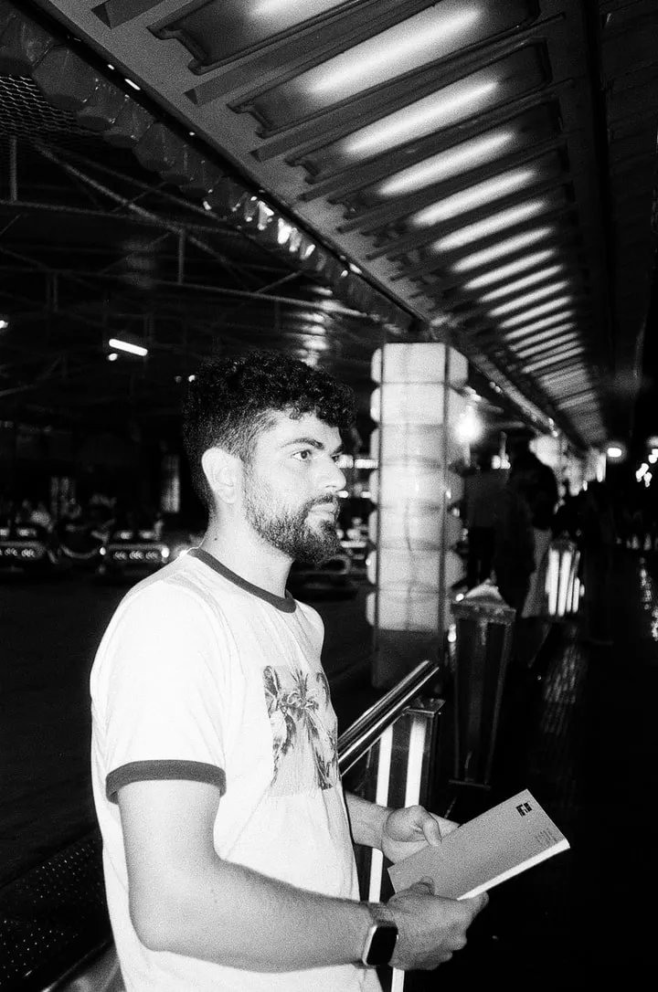 Fabio Biocchetti in profile at a funfair, holding a book.