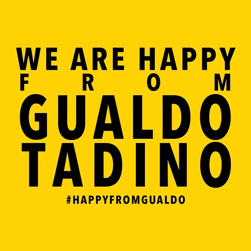 Yellow poster of the We are Happy from Gualdo Tadino video with the hashtag #happyfromgualdo